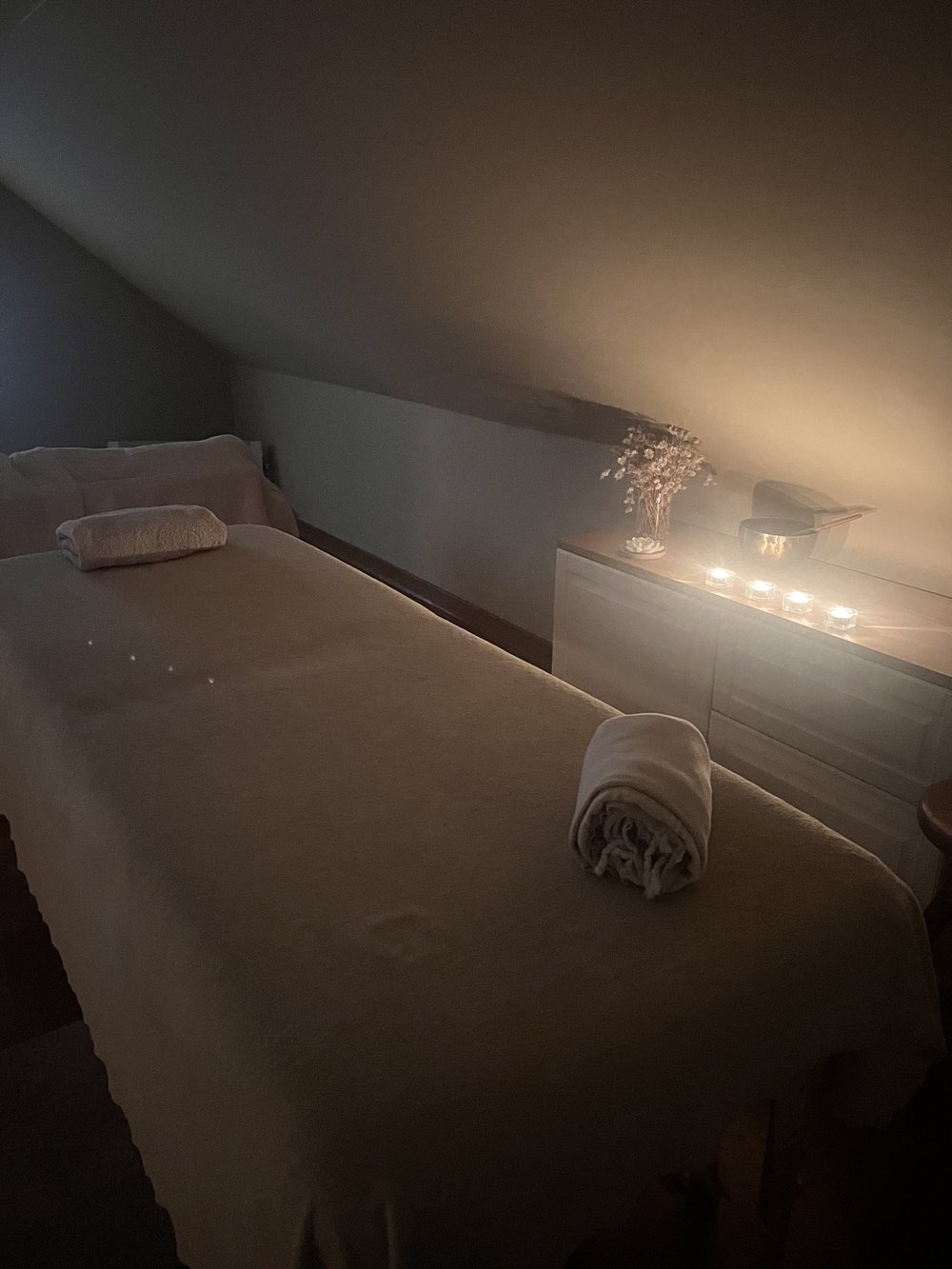Table de massage prête, bougies allumées et ambiance feutrée du cabinet à Braine-l'Alleud