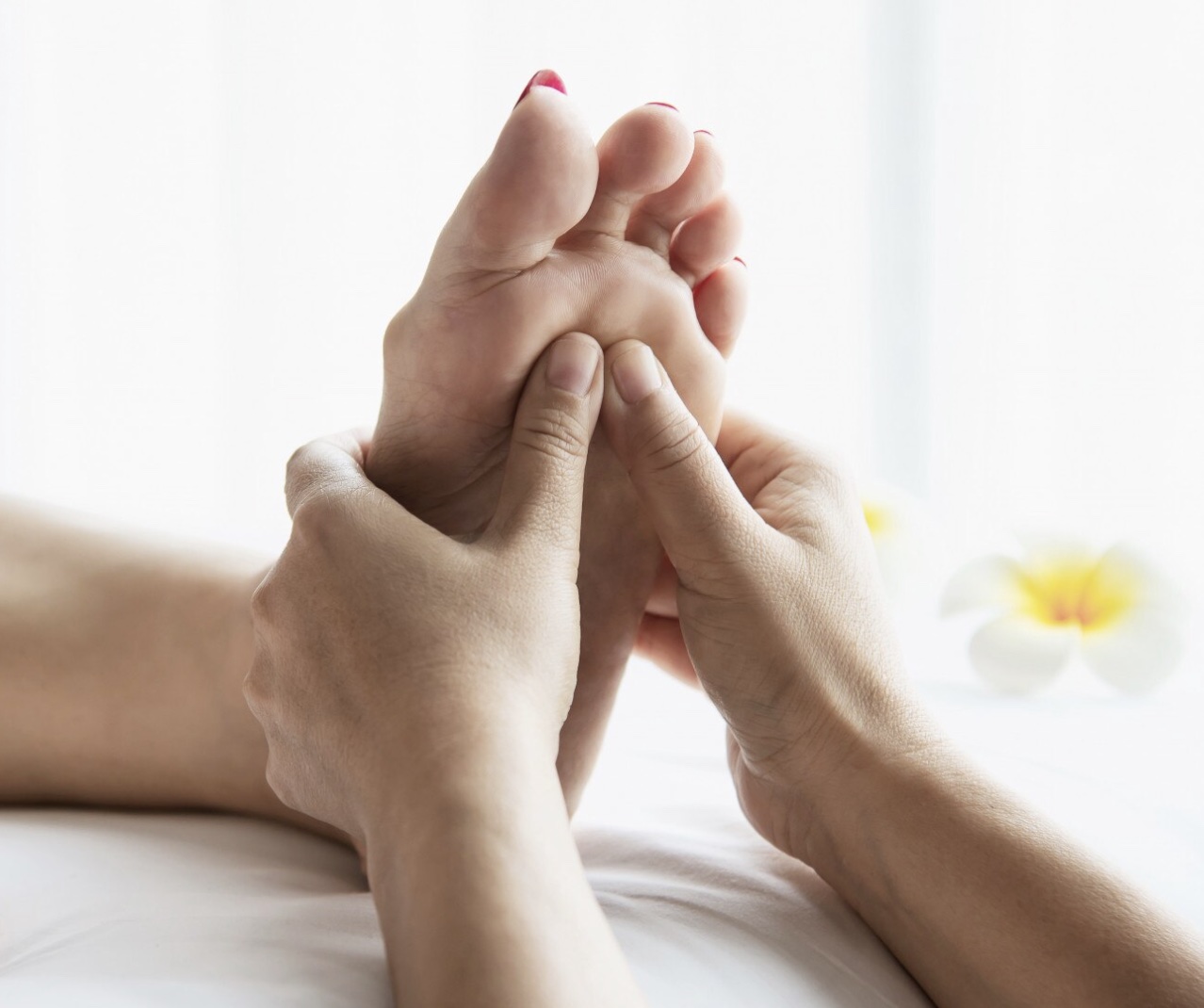 Séance de réflexologie plantaire, mains en pression sur le pied